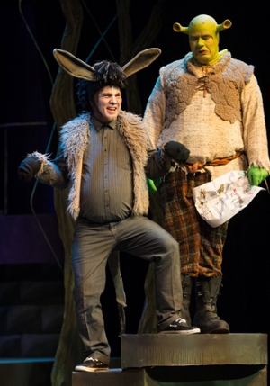 The donkey, played by Chris Kernan, smiles broadly while Shrek, played by Zac Farmer, looks on.