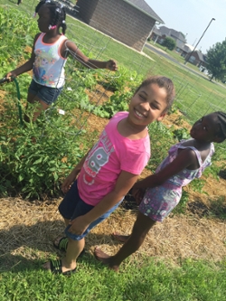 (L-R) Wilniya, Zarria and Shalise water the community garden they planted.