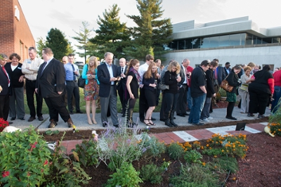 A crowd of attendees appreciates the newly-installed paver pathway at the School of Pharmacy’s Medicinal Garden.