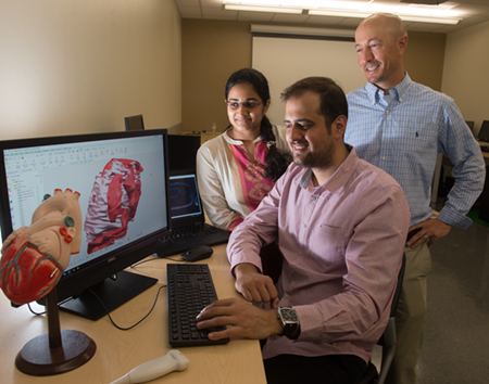 Graduate student Saygin Sop (seated) looks at a 3D model with fellow student Akhila Karlapalem, while Dr. Jon Klingensmith looks on.