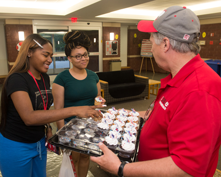Students Taliah Woodson, of Chicago, and Jayla White, of Springfield, smile as they take a cupcake from Chancellor Randy Pembrook during the House Calls welcome event.