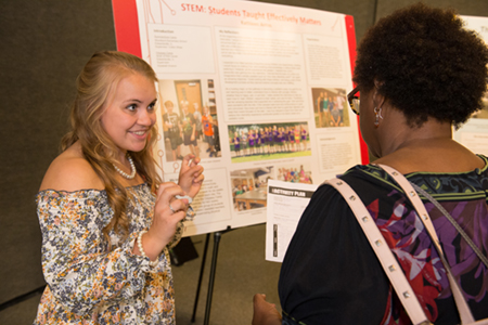 Noyce summer scholar Kathleen Antos, a sophomore nursing major, highlighted her summer experience working with students at Edwardsville’s Summer Zone and SIUE’s Odyssey Science Camps to a visitor at the showcase event.