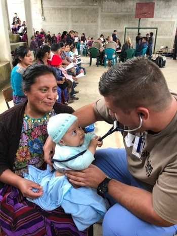 SIUE School of Nursing student Greg Jennings provides care for a baby in Guatemala.