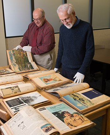 University Archivist and Special Collections Librarian Stephen Kerber, PhD, (front) and LIS History Subject Liaison Matt Paris (back) carefully view the extensive set of scrapbooks dating from the 1940s which have been donated to SIUE’s Library and Information Services. 