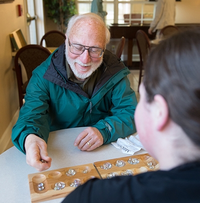 Meridian Village resident Brent Langley plays mancala with SIUE graduate student Katie Keener.