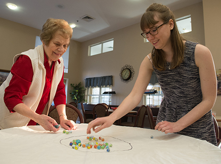 SIUE undergraduate Emily Deahr plays marbles with Meridian Village resident Alice Mueller.