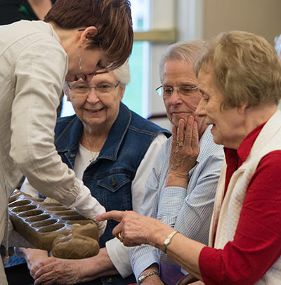 University Museum Collections Manager Erin Vigneau-Dimick shows Meridian Village residents artifacts from its collection. The featured residents include Dorothy Kueper, Joan Meier and Alice Mueller.