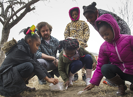 SIUE STEM Resource Center Manager Colin Wilson instructs a group of girls from Venice as they gather soil samples during their after-school urban gardening program.