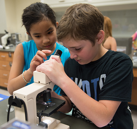 Odyssey Science Camp participants Samantha Hangsleben (left) and Brett Schoen work with a microscope.
