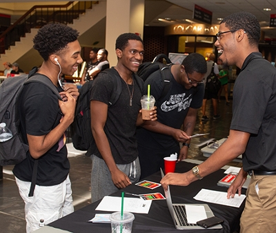 (L-R) Sophomore Vernon Smith, freshman Karriem Muhammad, and sophomore Jeremiah Ratfliff gain information on Collegiate 100 president Braxton McCarroll.