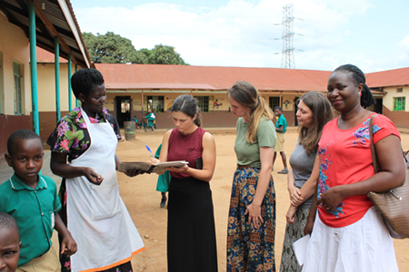 SIUE speech language pathology students Brianna Bowles, Sarah Geatley and Katherine Wilson, and Ugandan colleague Deborah Zawedde, signing the visitor’s register at a primary school in Seeta, Uganda. 