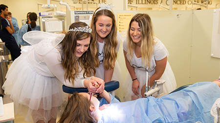 A group of tooth fairies offer encouragement to a child during the SIU SDM’s Give Kids a Smile Day.