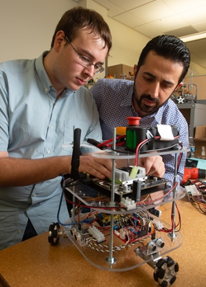 SIUE’s Nima Lotfi, PhD, looks on as junior computer science major Jacob Novosad works on a robot in the mechatronics and robotics lab.