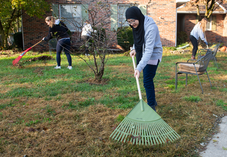 SIUE student Mariyam Alnoor helps rake the yard at a local residence.