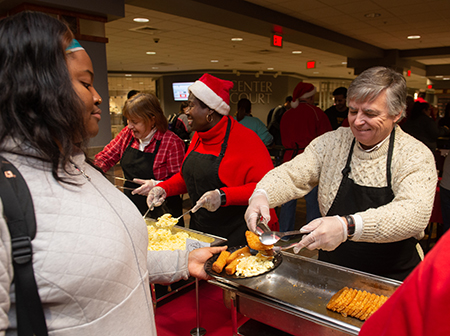 SIUE Chancellor Randy Pembrook serves hash browns to junior Eniola Awoniyi, of Chicago, during the annual Late Night Breakfast event.