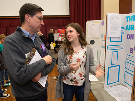 Julia Cox, an eighth-grade student at Maryville Christian School, describes her research project to volunteer judge Cem Karacal, PhD, dean of the SIUE School of Engineering.