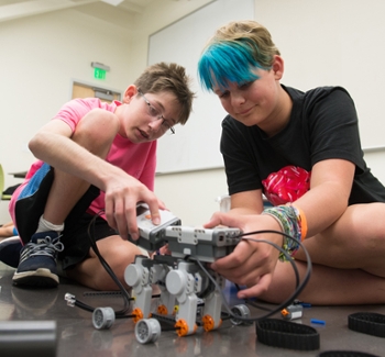 Odyssey Science Camp participants work intently to build and program a robot.