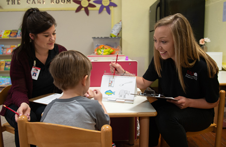 SIUE speech-language pathology graduate students Maren Valyo (left) and Hannah Greeling (right) lead a speech and language screening with a child at the Metro East Montessori School. 