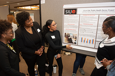 A team of public health students look over their poster presentation highlighting their Senior Assignment.