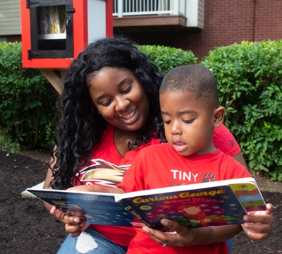 Melody Peterson and her son Princeton read a book from the Little Free Library that’s been installed in Cougar Village.