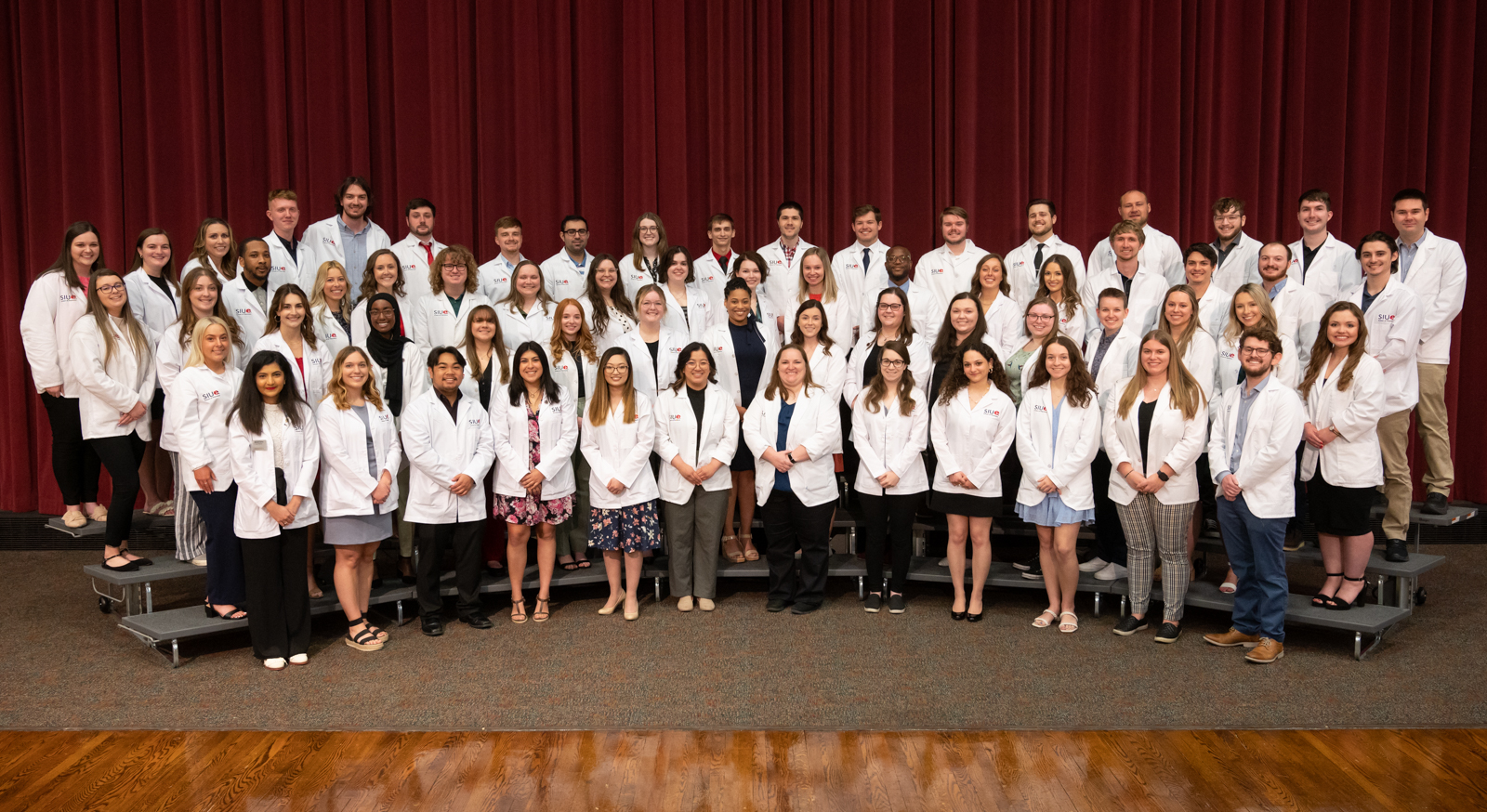 Group shot of about 60 pharmacy students in white coats. It is the School of Pharmacy 2023 at their pinning ceremony. 