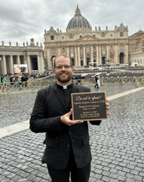 Father holding a plaque in St. Peter's Square
