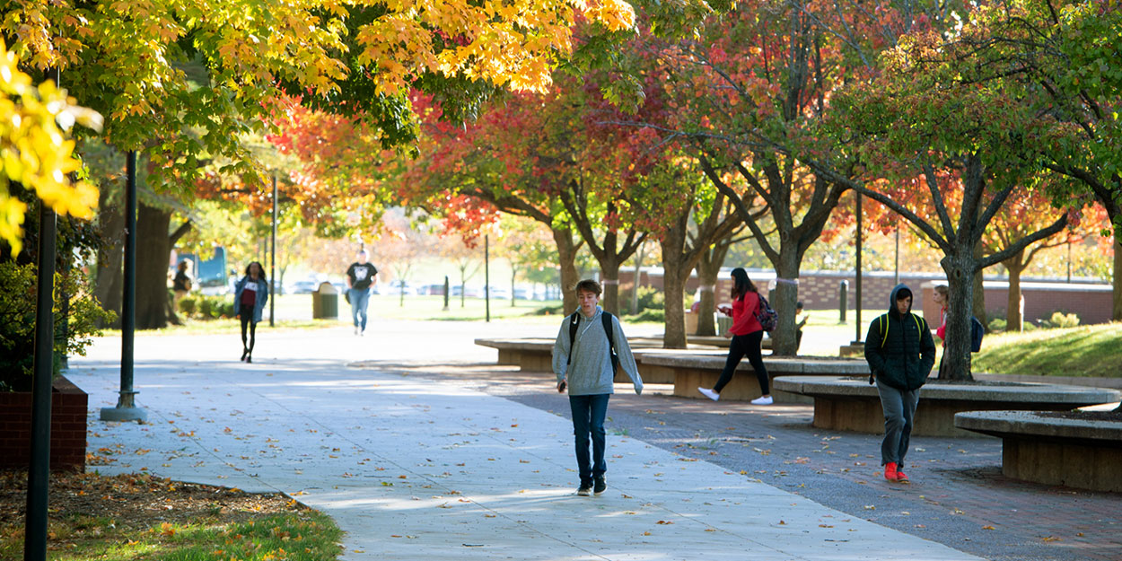 A student walking on the Stratton Quadrangle in front of Lovejoy Library in the afternoon at SIUE.