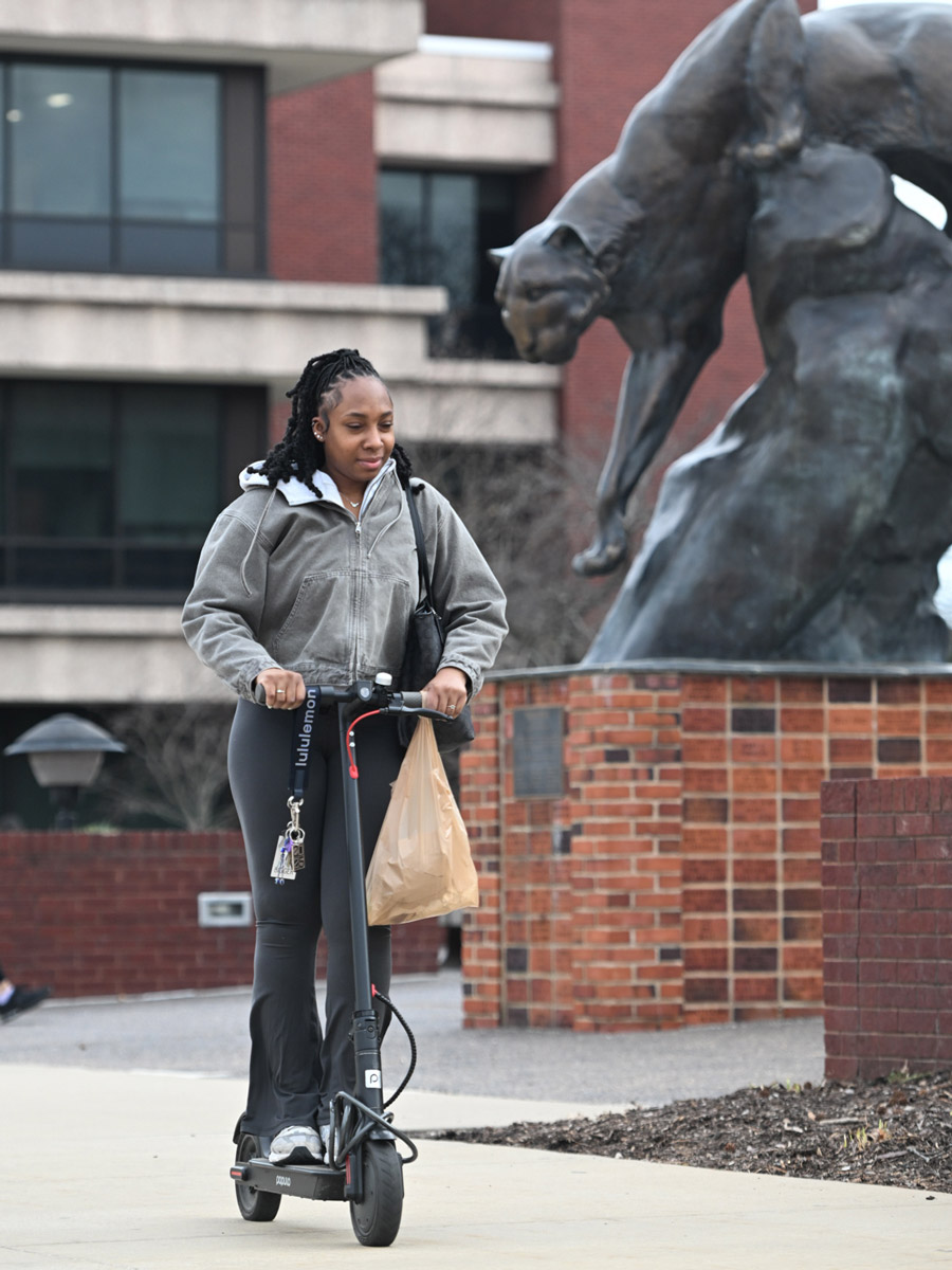 SIUE student riding a scooter. 