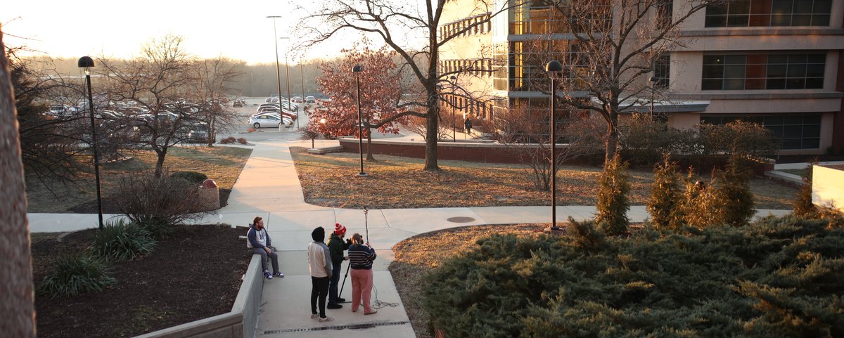 Mass Communications students filming on location outside Dunham Hall at golden hour