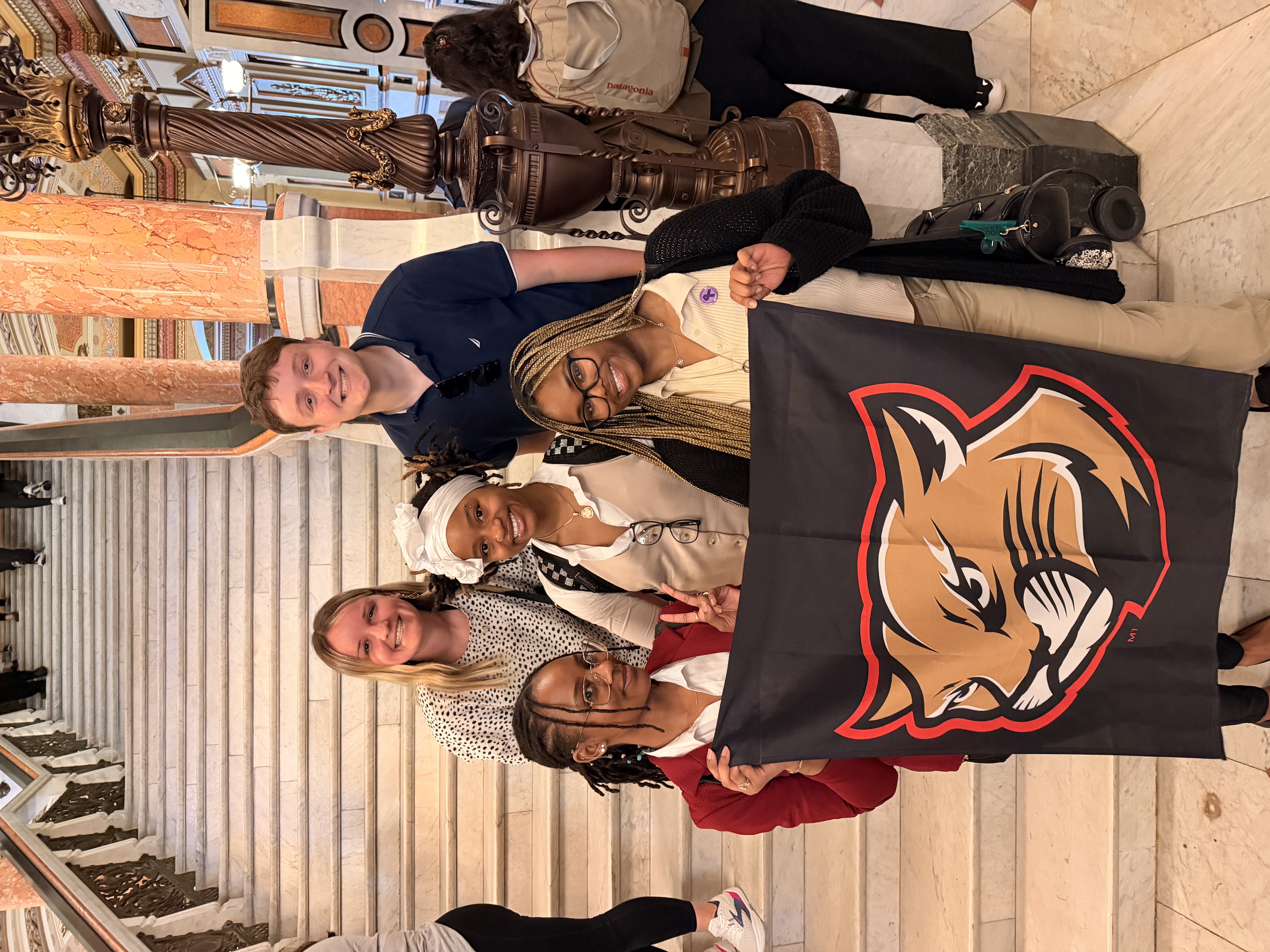 Five BSW students pose with the Cougar banner in the Illinois Capitol.