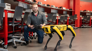 A SIUE engineering students works with a robot dog.