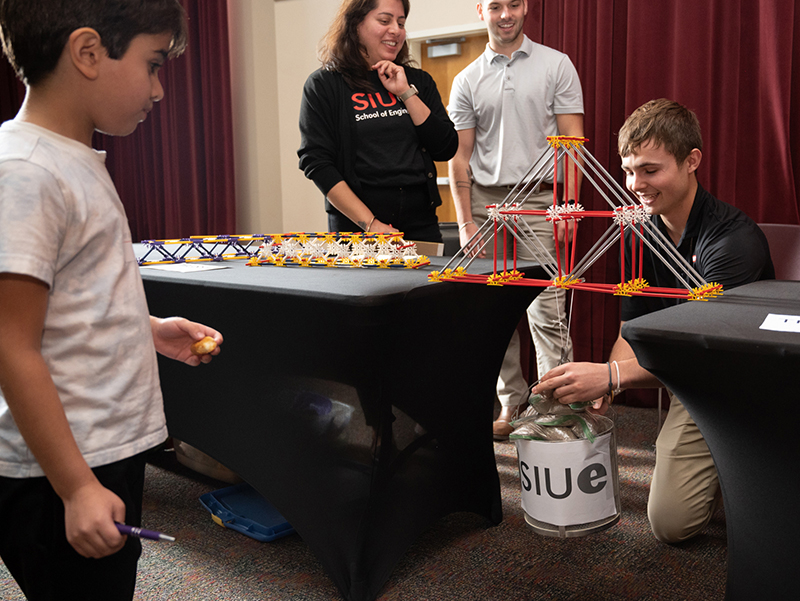 Engineering student showcasing a model bridge