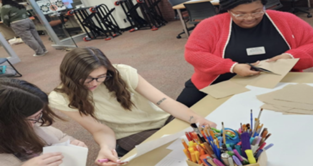 3 students around a table creating artwork