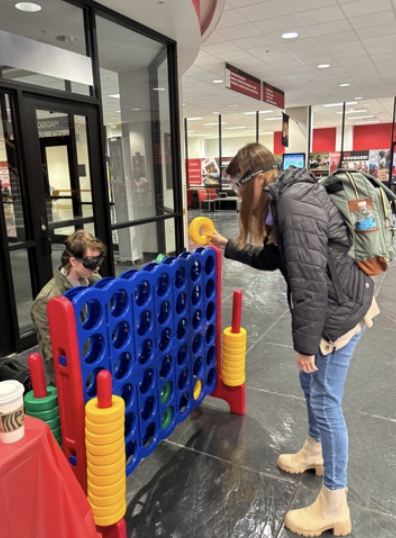 2 students playing giant connect 4 game while wearing drunk simulation goggles