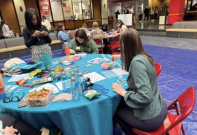 students sit around several round tables creating tshirts and blankets