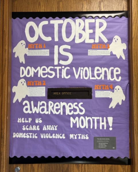 Door decorated with a purple background and white ghosts and text stating "October is domestic violence awareness month! help us scare away domestic violence myths"