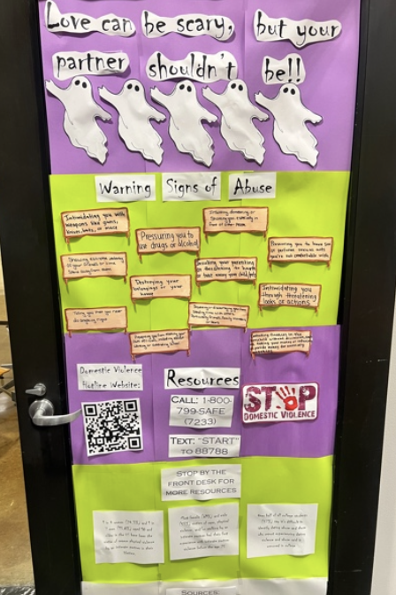 Door decorated with thick purple and green stripes and information about domestic violence 