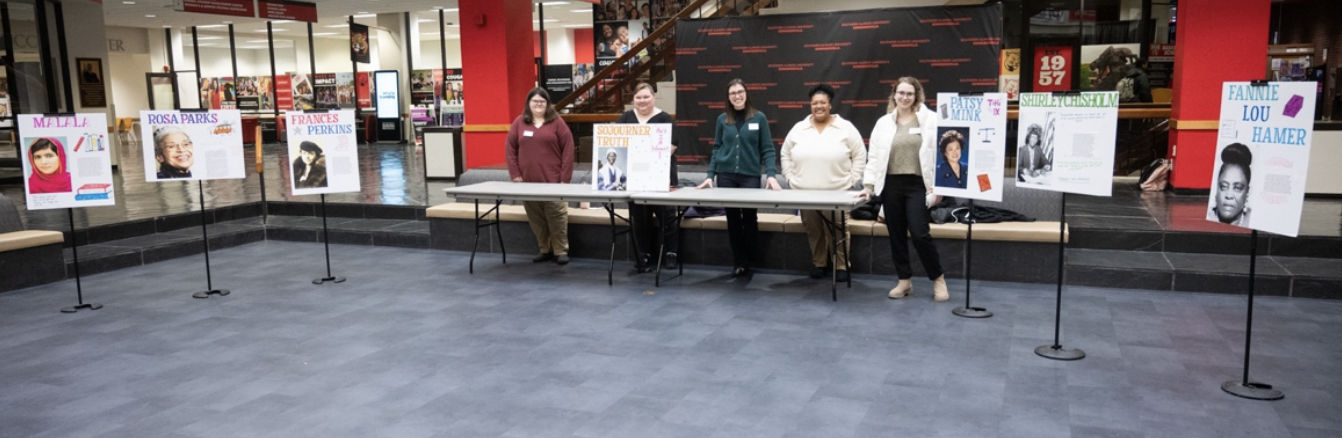 EOA practicum students stand with the posters of important women in history