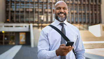 Smiling professional wearing a tie walking outside with phone