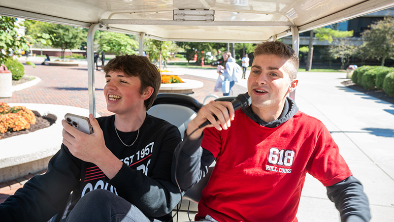 boys riding through campus in golf cart