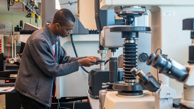 young man working on industrial machines in engineering lab