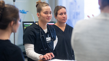 nursing student listening to instructor in simulation lab