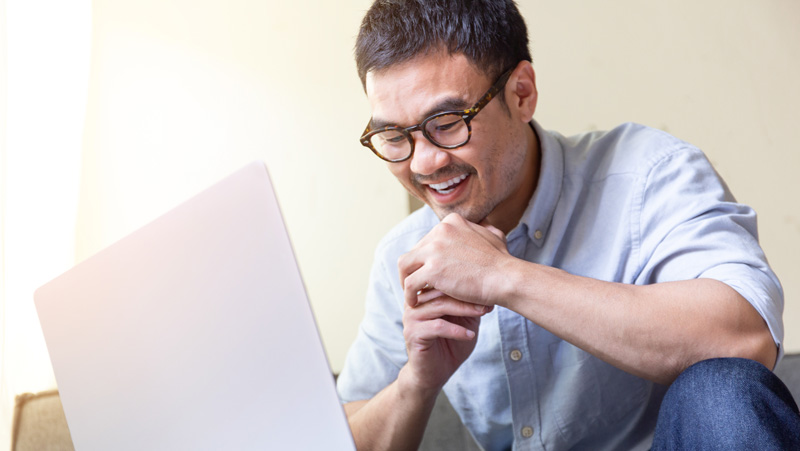 adult student laughing while using laptop