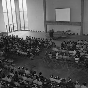 Freshmen wearing beanies attend an orientation session in the unfinished University Center ballroom.