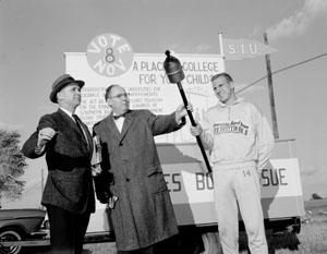 A student participant in the marathon run to Chicago (November 2-5, 1960) in support of the bond issue stands between Vice President Harold W. See (right) and Dr. H. Bruce Brubaker (left).