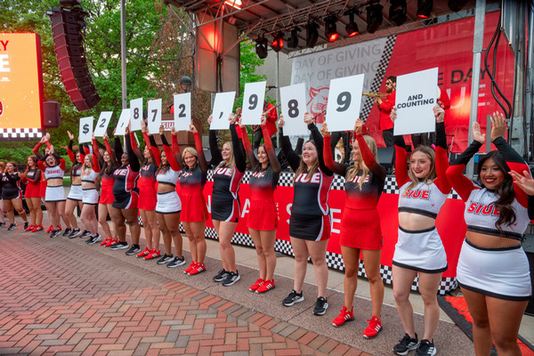 SIUE cheerleaders hold number signs on stage showing a fundraising total during the One Day One SIUE event.