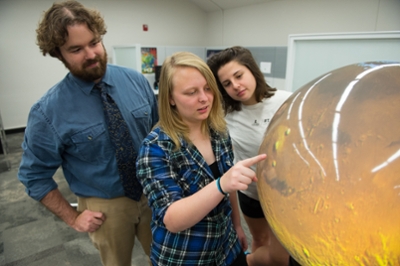 STEM Resource Center Manager Colin Wilson looks on as Valerie Becker and Emily Chappel examine a high-resolution image of the surface of Mars during last year’s Open House.
