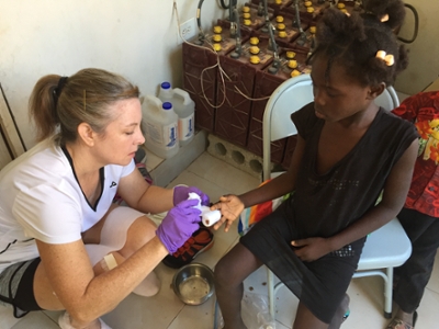 SIUE School of Nursing’s Dr. Valerie Griffin bandages a young girl’s finger during her medical mission trip to Saint-Marc, Haiti.