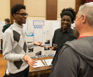two boys explaining their science project to a judge