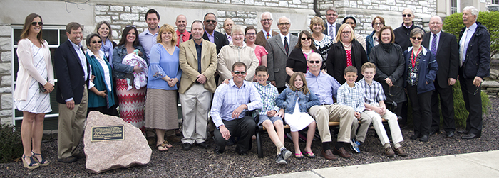 Dr. David Jenkins is surrounded by family, friends and former colleagues while seated on a bench dedicated in his name to the SIU School of Dental Medicine.